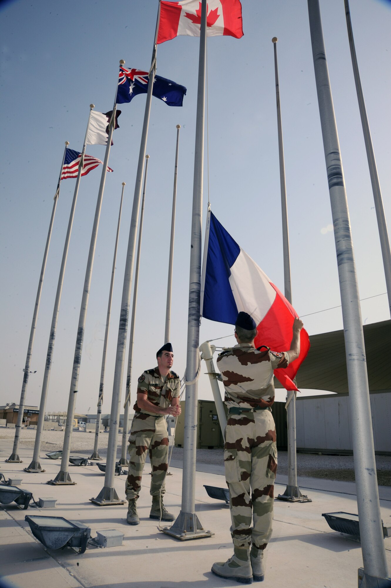 French Air Force Staff Sgts. Axel Michel and Damien Aubert raise the French flag at a Bastille Day ceremony during the 379th Air Expeditionary Wing, July 14, 2013. The taking of Bastille in 1789 signaled the beginning of the French Revolution. Michel and Aubert are Combined Air and Space Operations Center French Detachment telecommunications technicians. (U.S. Air Force photo/Senior Airman Bahja J. Jones) 