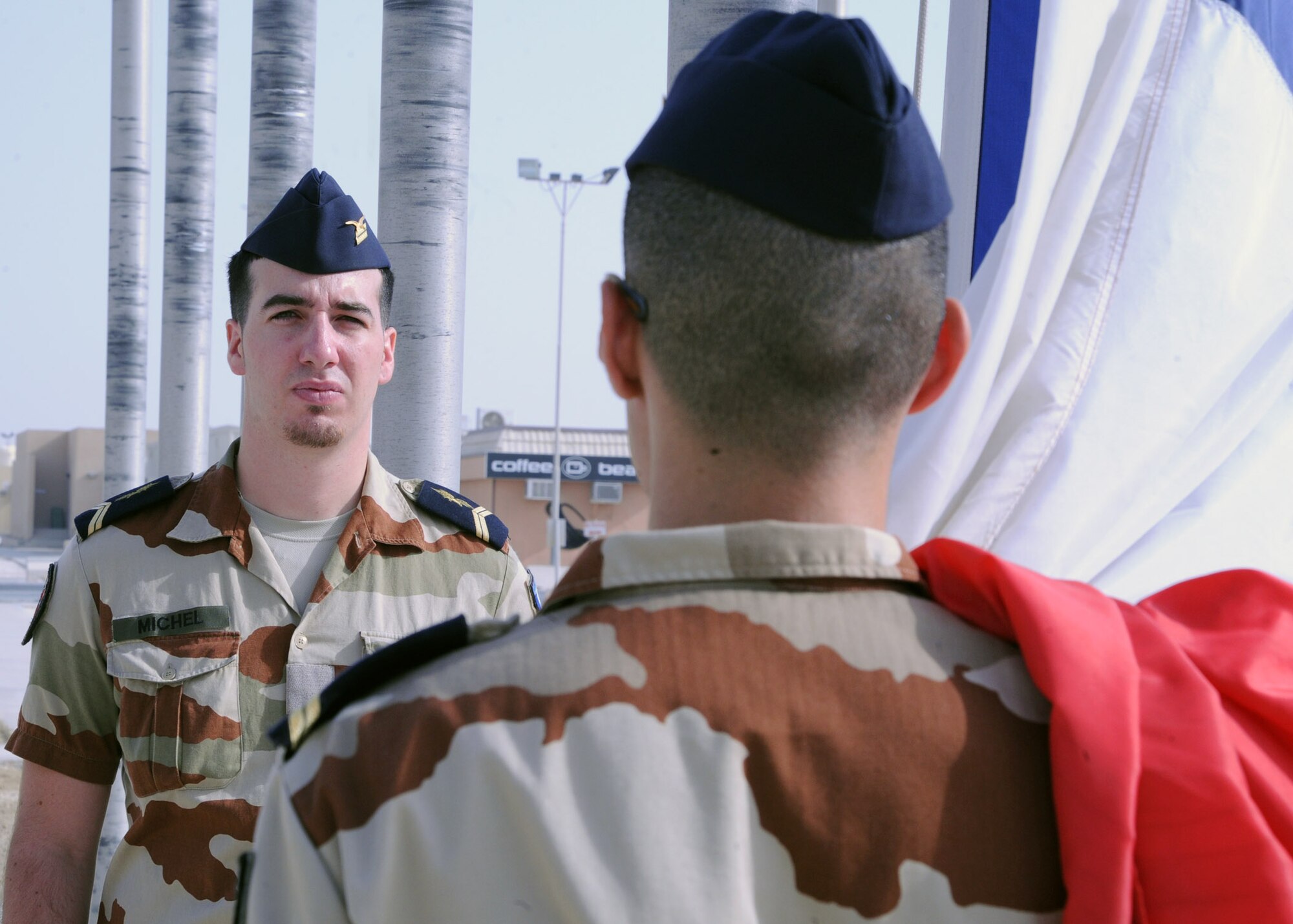 French Air Force Staff Sgts. Axel Michel and Damien Aubert stand at attention in preparation to raise the French flag during a Bastille Day ceremony at the 379th Air Expeditionary Wing in Southwest Asia, July 14, 2013. Bastille Day is a French holiday marking the anniversary of the fall of Bastille in Paris in 1789. Michel and Aubert are Combined Air and Space Operations Center French Detachment telecommunications technicians. (U.S. Air Force photo/Senior Airman Bahja J. Jones) 