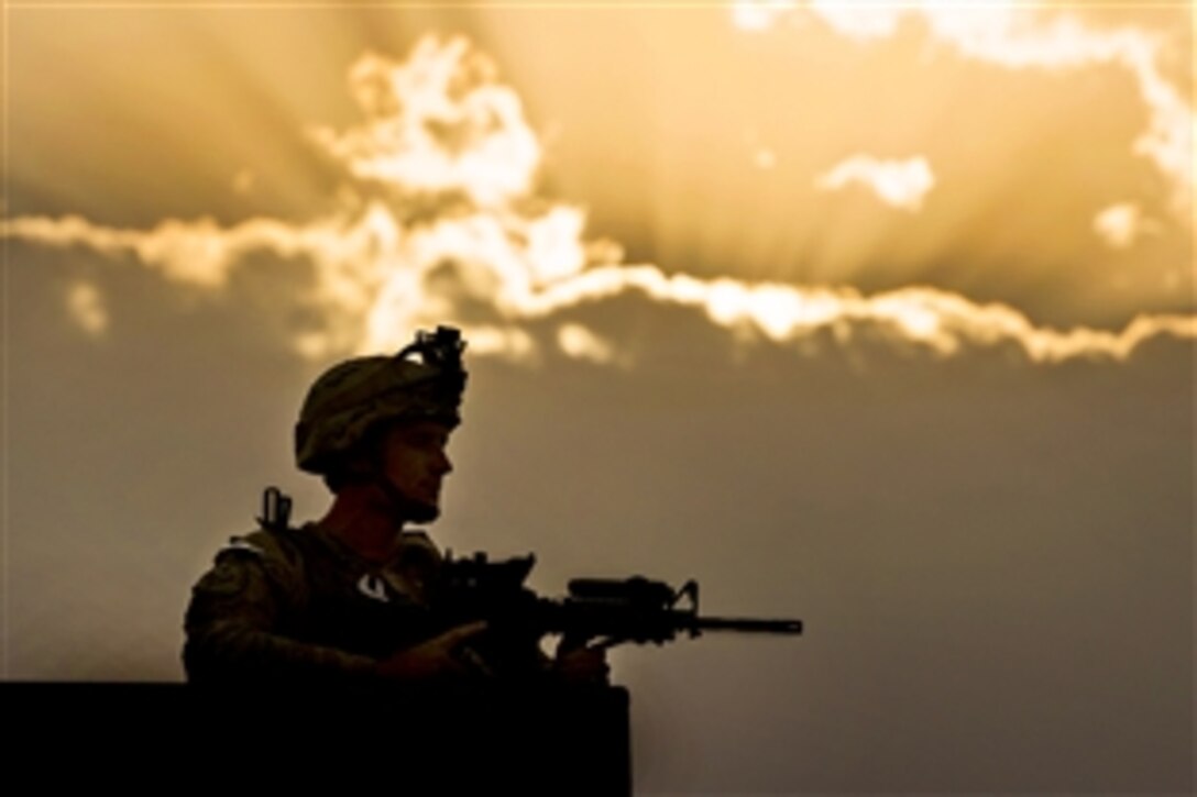 U.S. Air Force Airman 1st Class Alec Blackmon provides security from a rooftop as the sun sets on Camp Oqab in Kabul, Afghanistan, July 16, 2013. Blackmon is assigned to the 439th Air Expeditionary Advisory Squadron Security Forces. Camp Oqab is home to the 438th Air Expeditionary Wing, which is responsible for advising the growing Afghan air force.