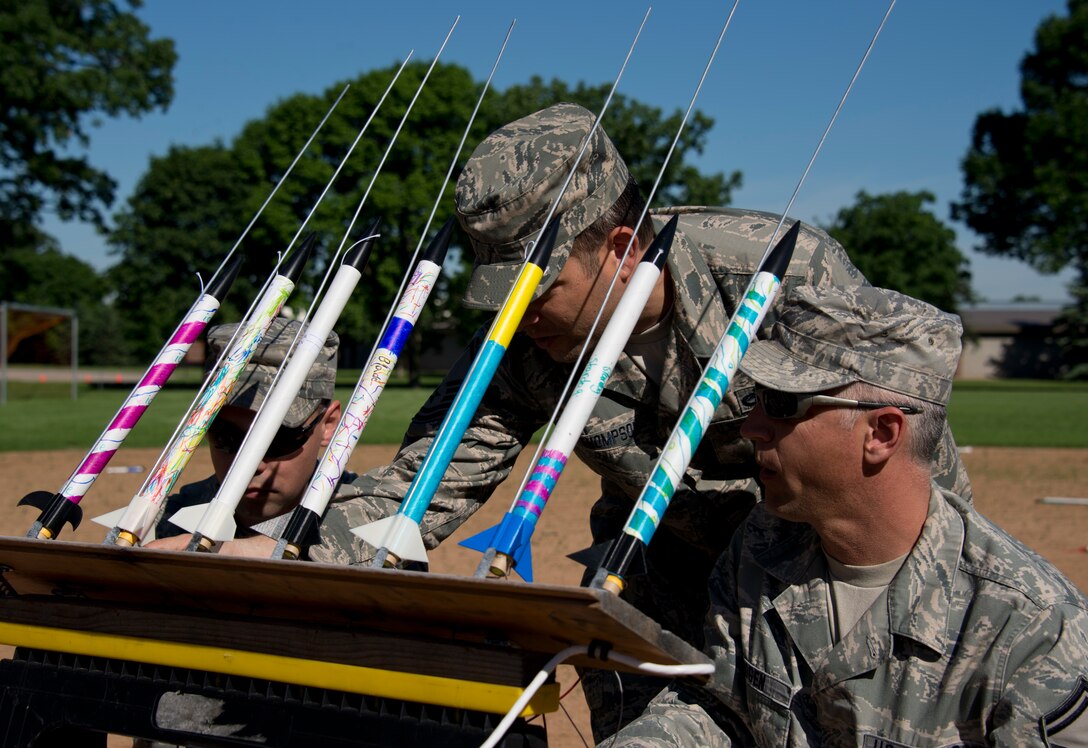 Master Sgt. Aaron Bayer, left, Master Sgt. Jason Thompson, and Senior Master Sgt. Chris Mogen attach wires to the rockets in St. Paul, Minn., Jun. 13, 2013. They are volunteering with the Starbase Minnesota’s rocket launch.
(U.S. Air National Guard photo by Tech. Sgt. Amy M. Lovgren/Released) 
