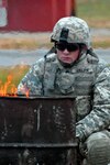 Sgt. Gordon Gilliam warms up next to a barrel fire while training at Camp Atterbury, Ind., for an upcoming deployment to Iraq. Gilliam is an armament repair sergeant from Lineville, Ala., in the 158th Support Maintenance Company, Alabama National Guard.