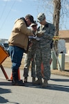 Spc. Barrett Troutman (right), of Tishomingo, and Spc. Timothy Stelly (center), of Ardmore, use a map to show a local man the cordoned off sections of Lone Grove, Okla. The Soldiers were providing security for any area of Lone Grove that was devastated by a tornado on Tuesday evening.