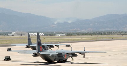 Two C-130s assigned to the 302nd Airlift Wing sit on the tarmac at Peterson Air Force Base, Colo. Four Modular Airborne Firefighting System-equipped C-130s from the 302nd and 153rd Airlift Wings have been assigned to support wildland fire fighting efforts in Colorado, dropping water and retardant on fires such as the Waldo Canyon fire burning in the background. 
