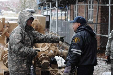 Sgt. Kimberly Boyce, water purification specialist, 401st Quartermaster Detachment, Lock Haven, Pa., discusses the best way to remove water out of a basement Nov. 7, 2012, with Carlos Malgonado, supervisor of grounds, Redfern Housing complex, Rockaway, N.Y. Residents at the complex have been without power since Hurricane Sandy hit the Northeast last week. Despite the effects of a second large storm, citizen-soldiers removed water from three buildings at the complex. The unit deployed into the area in direct support of the Federal Emergency Management Agency, state and local officials. 
