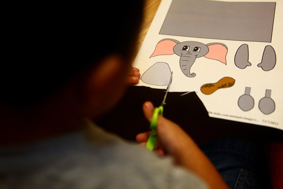 Julien, 5, cuts out portions of a paper elephant during arts and crafts time at the library aboard Marine Corps Air Station Miramar, Calif., July 17. Each book the children completed reading featured an elephant, making it a common theme for arts and crafts time.