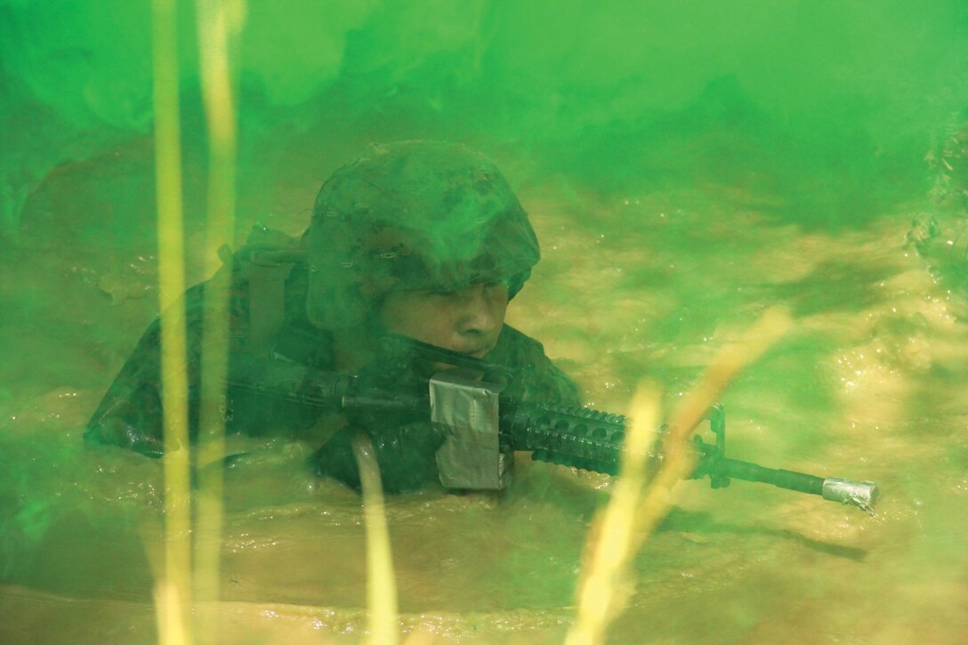 Lance Cpl. Victor Balbuena traverses the pit-and-pond obstacle of the endurance course July 15 at the Jungle Warfare Training Center on Camp Gonsalves. The pit-and-pond is one of 31 different obstacles the Marines must navigate through during the 3.8-mile endurance course. Balbuena is a water support technician with MWSS-172. Photo by Lance Cpl. Donald T. Peterson