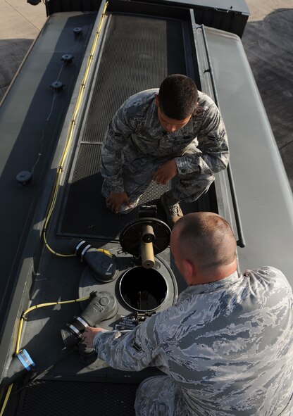 Airmen 1st Class Carlos Hernandez, top, and Shane Ashton, 2nd Logistics Readiness Squadron fuel distribution, look inside the utility port of an R-11 fuel truck on Barksdale Air Force Base, La., July 18, 2013. Fuels Airmen look inside the utility port to ensure the truck has the correct fuel level. If the fuel level is too high, it means fuel was not removed before refueling the truck. (U.S. Air Force photo/Airman 1st Class Benjamin Gonsier)