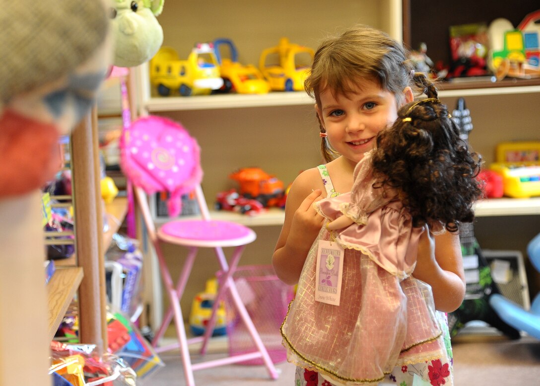 Ellie Junkins, daughter of Jacque Junkins, hugs on to a doll in the childrens section of the newly remodeled Thrift Shop July 16.  The Thrift Shop recently went under renovations to better organize items such as clothing and toys. (U.S. Air Force Photo/ Airman 1st Class Stephanie Englar)