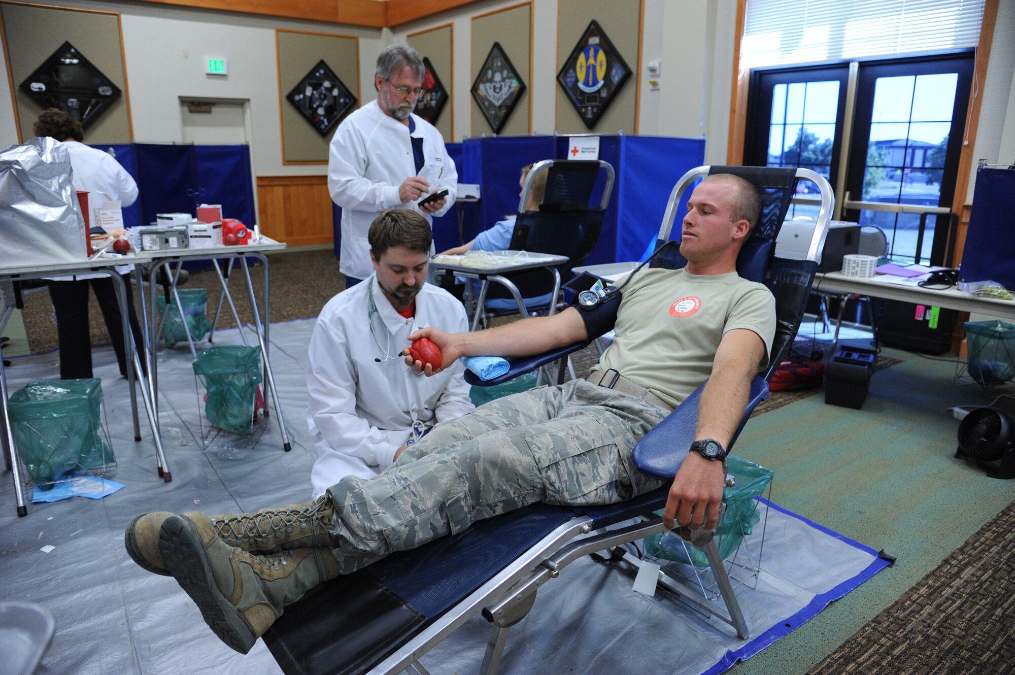 David Wall, Great Falls American Red Cross phlebotomist, prepares Senior Airman Tracy Wetzel, 819th RED HORSE Squadron pavement and equipment operator, to donate blood during a monthly blood drive at the Grizzly Bend on July 16. Wetzel, who has a universal blood type, donates as often as he can. (U.S. Air Force photo/Senior Airman Katrina Heikkinen)