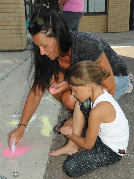 Lisa Broussard and her daughter, Sophia, 5, draw a picture with chalk during the 14th annual Chalk it Up sidewalk chalk art competition at the Malmstrom Air Force Base Youth Center on July 11. More than 100 children from the YC and Child Development Center participated. (U.S. Air Force photo/Senior Airman Katrina Heikkinen)