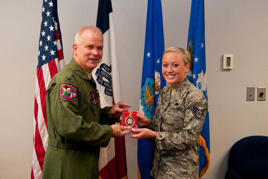 Col. William Dehaes, Commander 132nd Fighter Wing (132FW), Des Moines, Iowa, presents a gold recruitment badge to Staff Sgt. Sabrina Blake on July 18, 2013. The 132nd recruitment and retention team was recognized as the best out of a nine-state region during FY12.   (U.S. Air National Guard photo by Senior Airman Dustin M. Smart/Released)