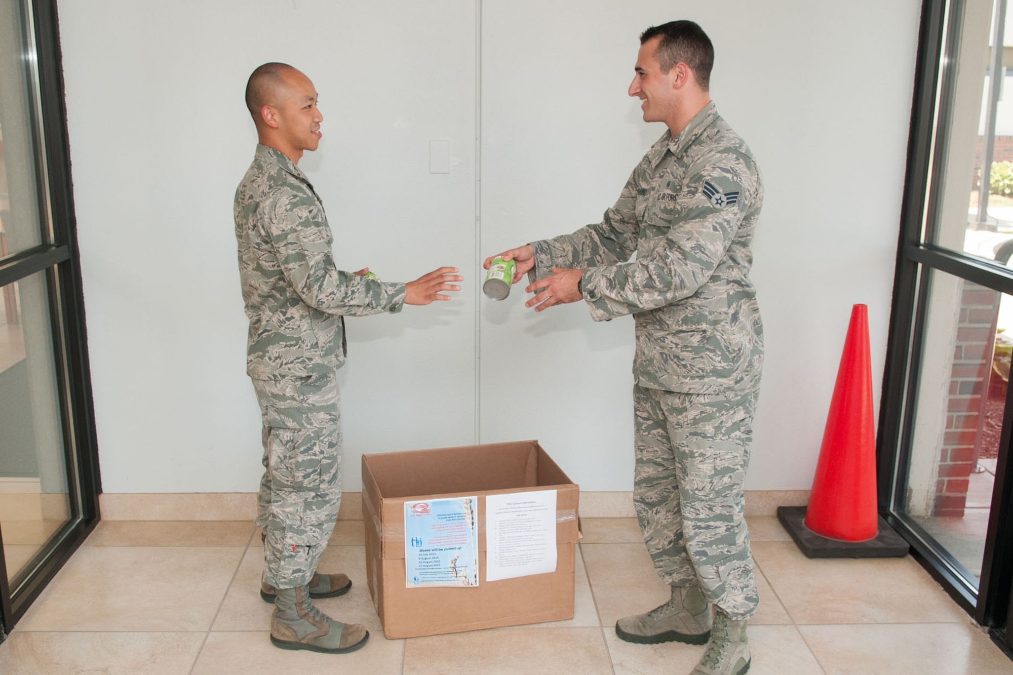 HANSCOM AIR FORCE BASE, Mass. -- Senior Airman Thomas Membrino, 66th Medical Squadron, donates to 2nd Lt. Tan Pham, the base food drive coordinator, a canned item for the Feds Feed Families drive box located in the Clinic foyer, July 16. Donations collected on base will be donated to the Greater Boston Food Bank. The GBFB is facing severe shortages of non-perishable items and Hanscom volunteers are organizing a food collection that will run through Aug. 28 with the placement of marked collection boxes at various locations throughout base. (U.S. Air Force photo by Rick Berry)