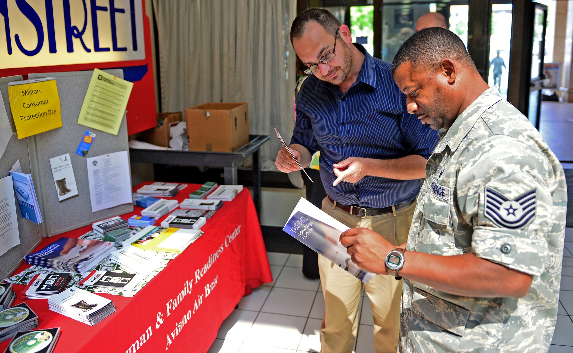 Kevin Hamilton speaks to Tech. Sgt. Otis Clay about various scams and how to avoid them during Military Consumer Protection Day, July 17, 2013, at Aviano Air Base, Italy. The purpose was to educate military members and families on frauds and scams and how they can protect themselves. Hamilton is with the 31st Force Support Squadron as a community readiness consultant and Clay is with the 31st Logistics Readiness Squadron. (U.S. Air Force photo/Airman 1st Class Matthew Lotz)