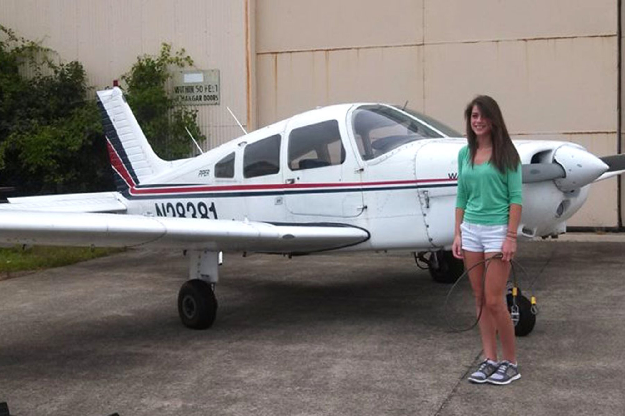 HANSCOM AIR FORCE BASE, Mass. – Seventeen-year-old Nicole Case stands in front of a Hanscom Aero Club Piper Warrior aircraft prior to take-off with her father on the flightline here July 13. The soon-to-be senior in high school recently received her pilot's license from the Aero Club, becoming the youngest member of the club to accomplish that. (Courtesy photo)