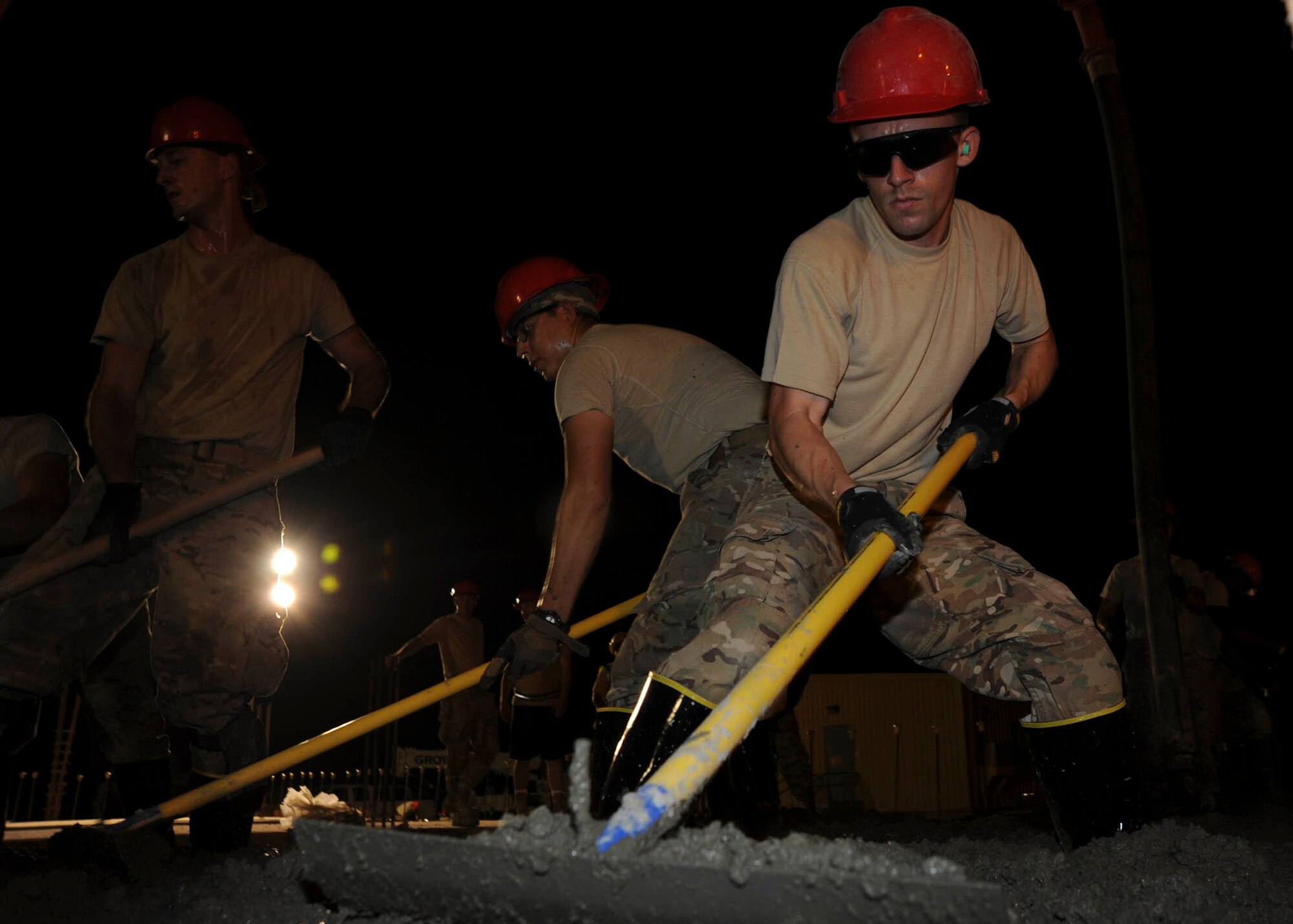 Senior Airman Lance Mendelson uses a concrete rake to distribute wet concrete at the 379th Air Expeditionary Wing in Southwest Asia, July 9, 2013. The 557th Expeditionary RED HORSE Squadron is building a Contingency Aeromedical Staging Facility that will house and provide medical care to wounded service members prior to medical evacuation. Mendelson is a 557th ERHS water and fuels systems maintenance journeyman deployed from Malstrom Air Force Base, Mont. (U.S. Air Force photo/Senior Airman Bahja J. Jones) 