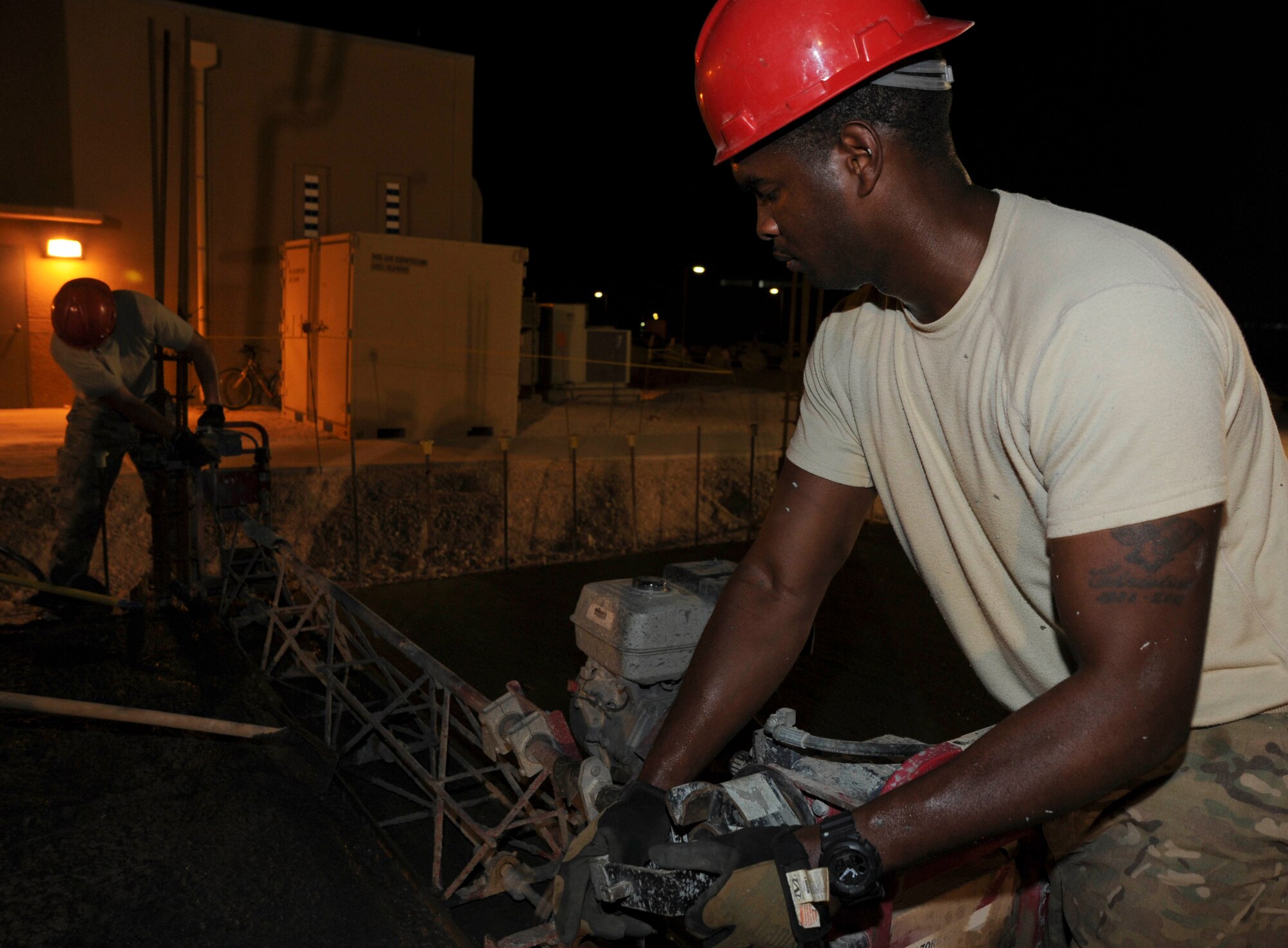 Staff Sgts. Paul Williams and William Ferguson use a screed to smooth and level wet concrete at the 379th Air Expeditionary Wing in Southwest Asia, July 9, 2013. Williams and Ferguson are 557th Expeditionary RED HORSE Squadron structural craftsmen deployed from Malstrom Air Force Base, Mont. (U.S. Air Force photo/Senior Airman Bahja J. Jones) 