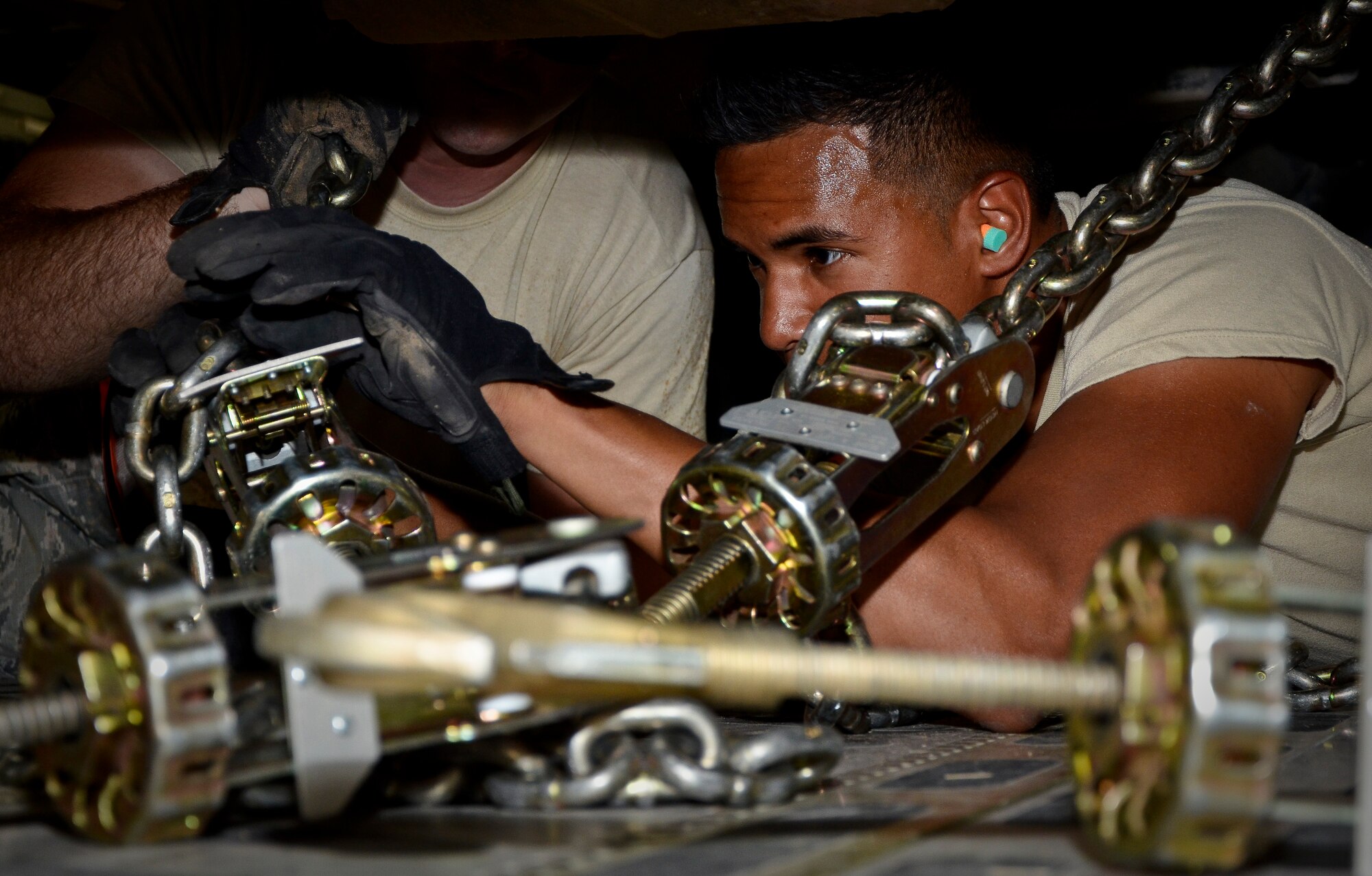 Senior Airman Marcanthony Khan secures an excavator with chains onboard a C-17 Globemaster III at the 379th Air Expeditionary Wing in Southwest Asia, July 17, 2013. Khan is an 8th Expeditionary Air Mobility Squadron air transportation technician deployed from Joint Base Charleston, S.C. (U.S. Air Force photo/Senior Airman Benjamin Stratton)
