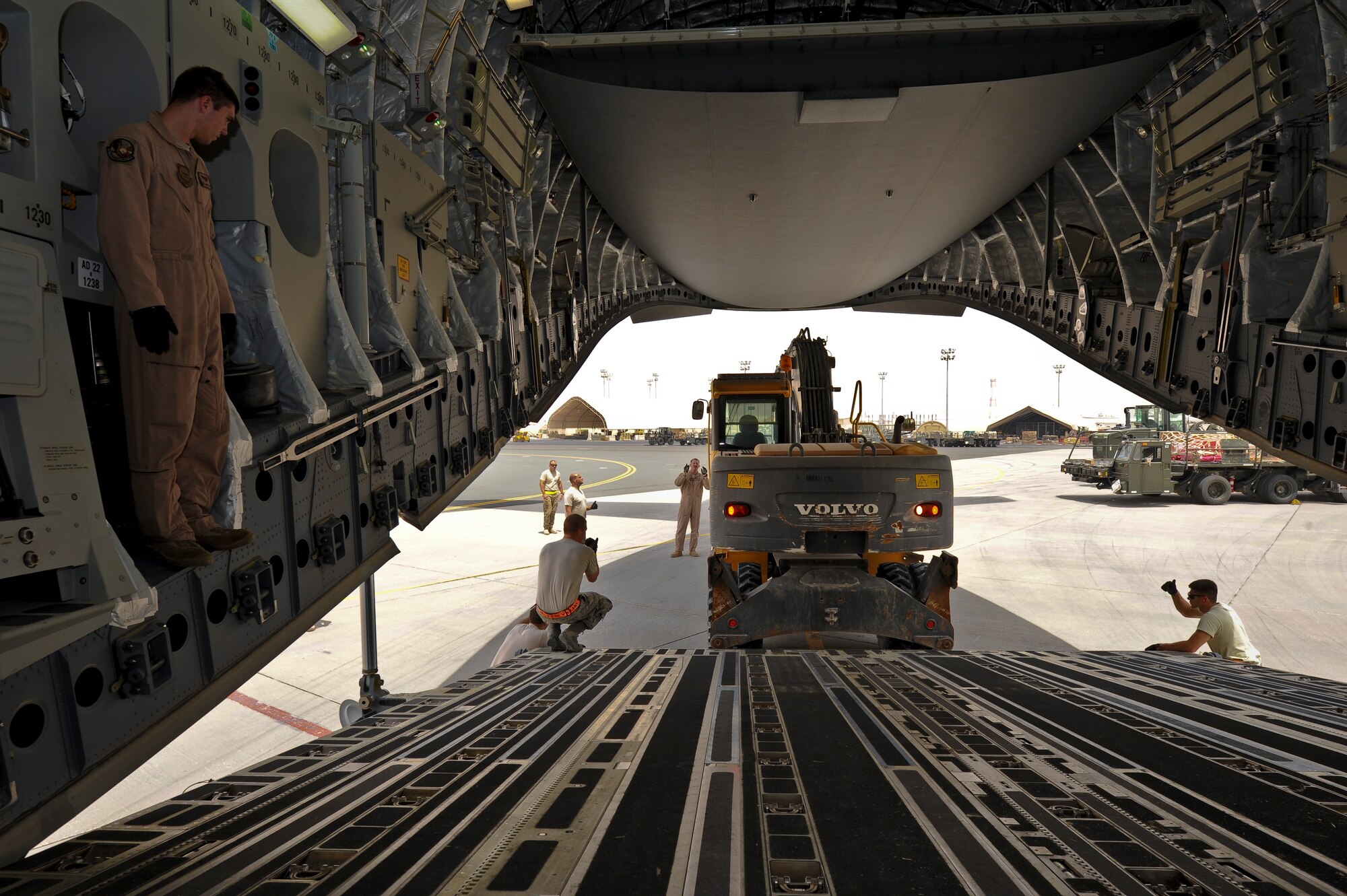 Airmen from the 8th Expeditionary Air Mobility Squadron, 557th Expeditionary RED HORSE Squadron and loadmasters from the 816th Expeditionary Airlift Squadron load an excavator onto a C-17 Globemaster III at the 379th Air Expeditionary Wing in Southwest Asia, July 17, 2013. The C-17 will fly the heavy equipment to a forward operating location in Afghanistan where 1st Expeditionary Civil Engineer Group units will use it to support ongoing Operation Enduring Freedom missions. (U.S. Air Force photo/Senior Airman Benjamin Stratton)