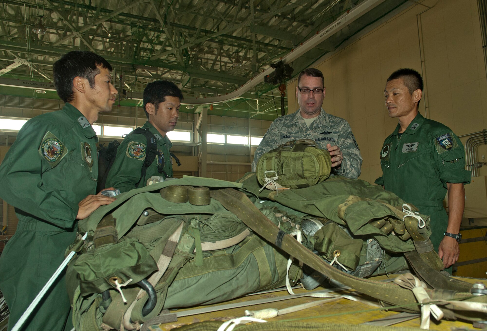 Master Sgt. Eric Gaul, 36th Airlift Squadron, shows Japan Air Self-Defense Force members how to properly secure a parachute to a heavy airdrop platform cargo load at Yokota Air Base, Japan, July 12, 2013. Yokota employs G12E parachutes which can support up to 2,200 pounds. (U.S. Air Force photo by Senior Airman Michael Washburn)