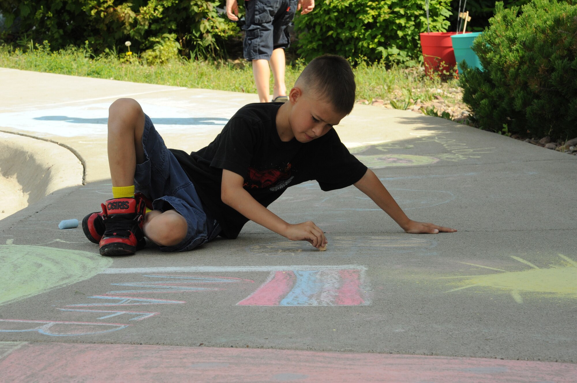 George Broussard, 8, son of Tech. Sgt. Christian Broussard, 341st Logistics Readiness Squadron unit deployment manager, colors in a design during the annual sidewalk art competition at the Malmstrom Air Force Base Youth Center on July 11. The theme this year was “Montana.” (U.S. Air Force photo/Senior Airman Katrina Heikkinen)