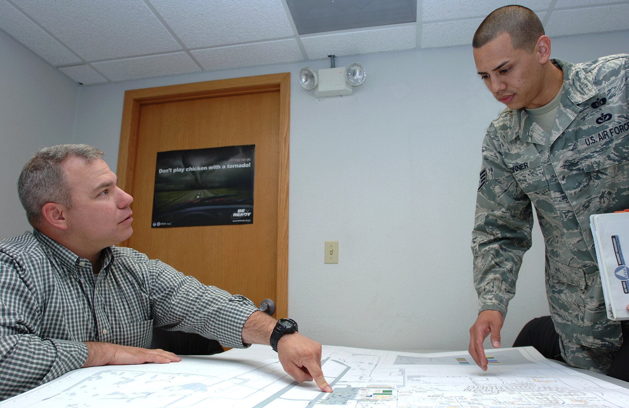 Norman Becker, 319th Civil Engineer Squadron emergency management and readiness flight chief, discusses a future base-wide exercise with Staff Sgt. Shaun Zinner, 319th CES NCO-in-charge of plans and operations, on July 17, 2013, on Grand Forks Air Force Base, N.D. Becker was named the Warrior of the Week for the third week of July 2013.(U.S. Air Force photo/Airman 1st Class Zachiah Roberson)