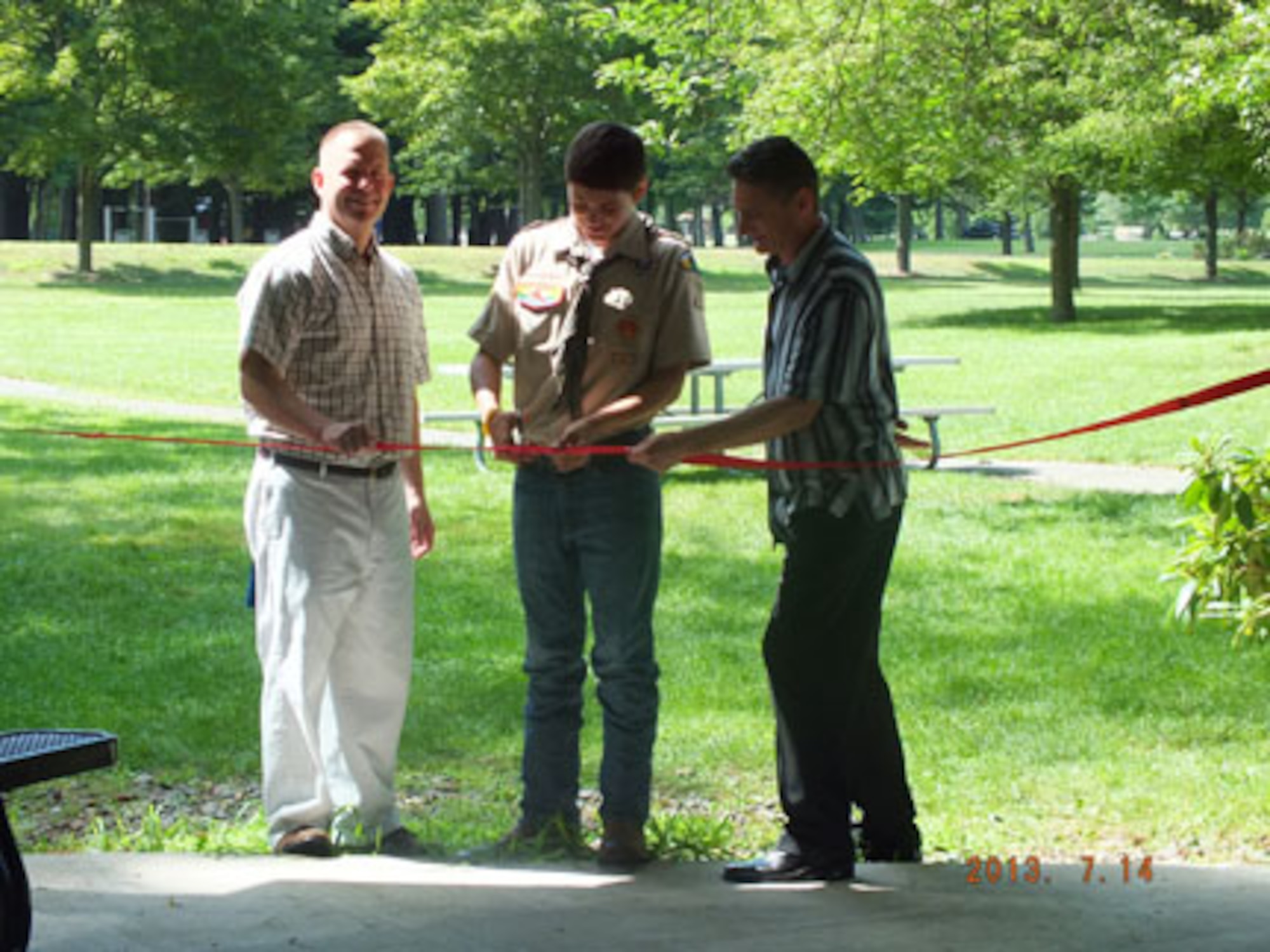 HANSCOM AIR FORCE BASE, Mass. – Dean Glenn (center), cuts the ribbon along with Chaplain (Maj.) Robert Borger (right) and his father, Col. Frank Glenn, 66th Medical Squadron commander, at the newly renovated gazebo at the Hanscom Chapel. Dean is a local Boy Scout that refurbished the gazebo as a final Eagle Scout project June 22 and 23. (Courtesy photo)