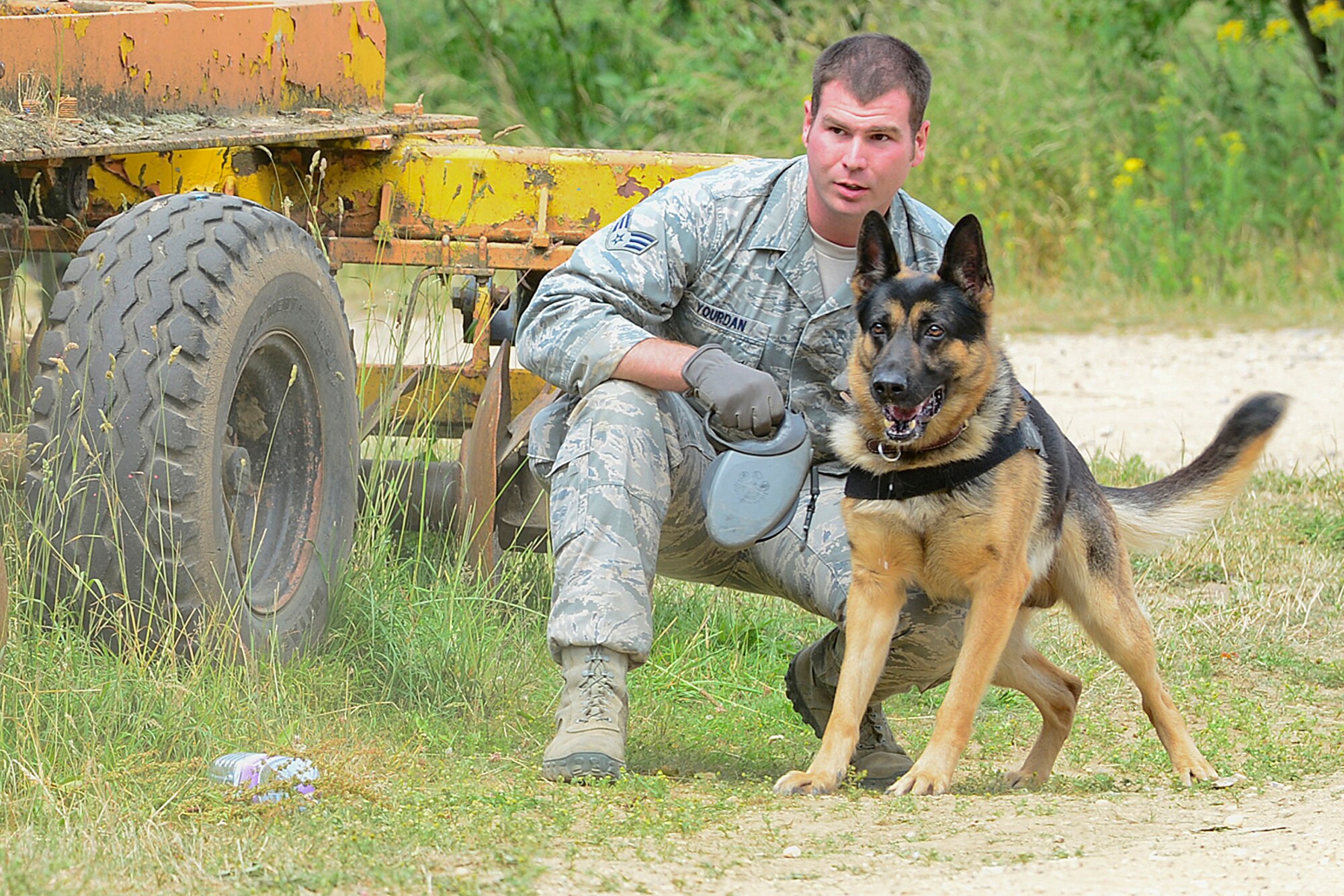 STANFORD TRAINING AREA, England – Senior Airman Matt Yourdan, 48th Security Forces Squadron military working dog trainer, holds back Ayron, a 5-year-old German Shepherd MWD, during force-on-force training at the Stanford Training Area in Norfolk, July 11, 2013. Members from the 48th SFS conducted a three-day training exercise at STANTA, an area that offers a realistic environment to help train Airmen. Defenders from the 100th SFS, RAF Mildenhall, assisted this training by playing as opposing forces. (U.S. Air Force photo by Airman 1st Class Dana J. Butler)