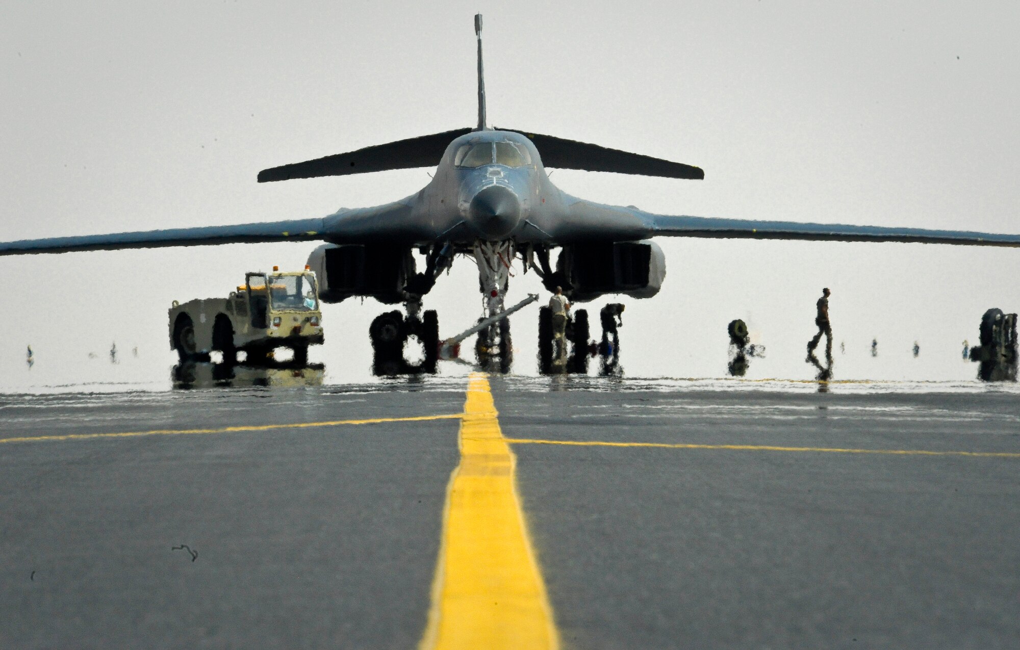 B-1B Lancer crew chiefs from the 34th Aircraft Maintenance Unit work to fix a blown tire as the sun heats up the tarmac at the 379th Air Expeditionary Wing in Southwest Asia, July 15, 2013. As these crew chiefs repair the blown tire, 379th Expeditionary Maintenance Group B-1 quality assurance inspector, Staff Sgt. Daniel Sanney, ensures the work is completed following safety guidelines. Sanney and these crew chiefs are deployed from Ellsworth Air Force Base, S.D. (U.S. Air Force photo/Senior Airman Benjamin Stratton)