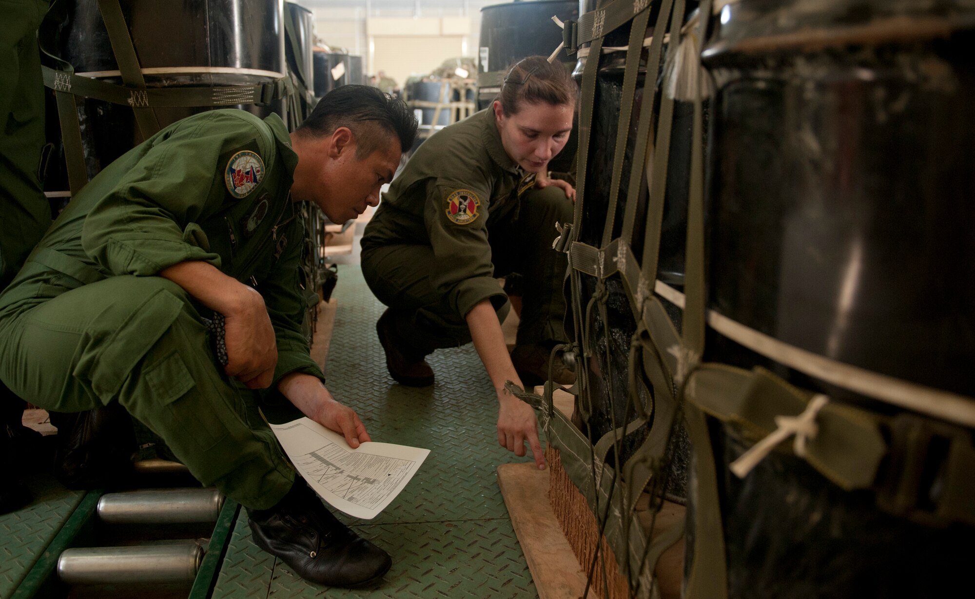 Staff Sgt. Monica Oshin, 36th Airlift Squadron, shows a Japan Air Self-Defense Force member the dissipating material, also known as honeycomb, on a containerized delivery system load at Yokota Air Base, Japan, July 12, 2013. These types of loads use a high-velocity parachute that is designed to stabilize the cargo and keep it from falling on its side. (U.S. Air Force photo by Senior Airman Michael Washburn)