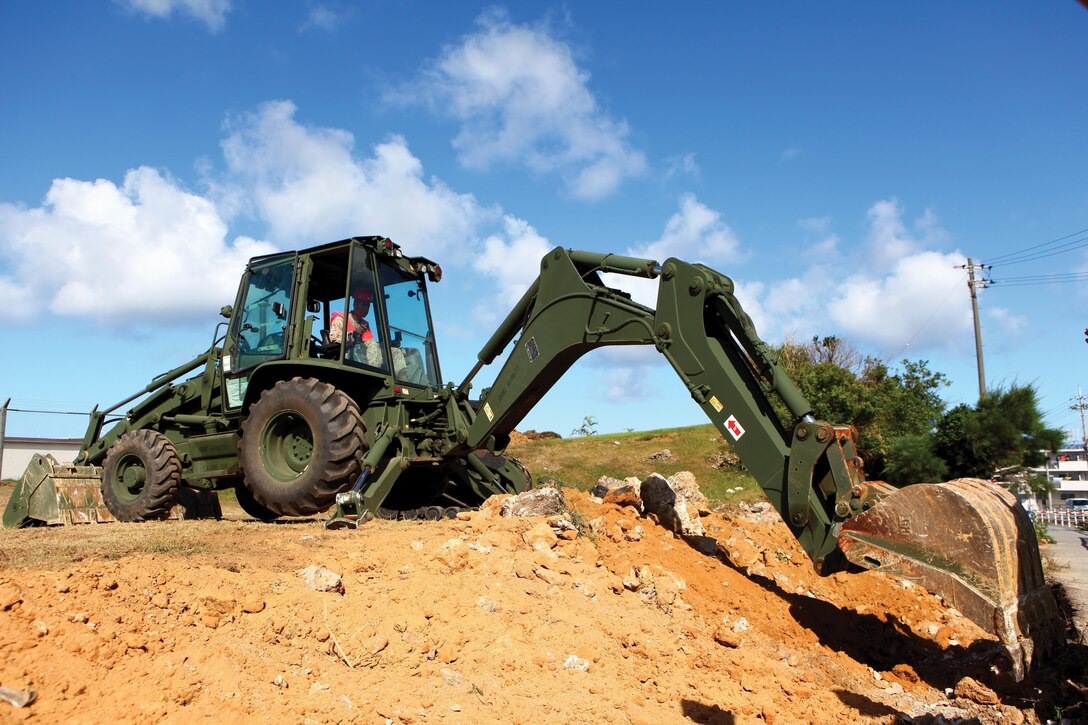 Lance Cpl. Raheem J. Boyd uses a 420D IT backhoe loader to excavate rocks July 8 during the removal of a 60-meter-long wall near U.S. Army Garrison Torii Station’s main gate. Working near private property, the Marines focused on carefully and deliberately completing the project without impacting the surrounding area. Boyd is a heavy-equipment operator with 9th Engineer Support Battalion, 3rd Marine Logistics Group, III Marine Expeditionary Force. Photo by Lance Cpl. Jose D. Lujano