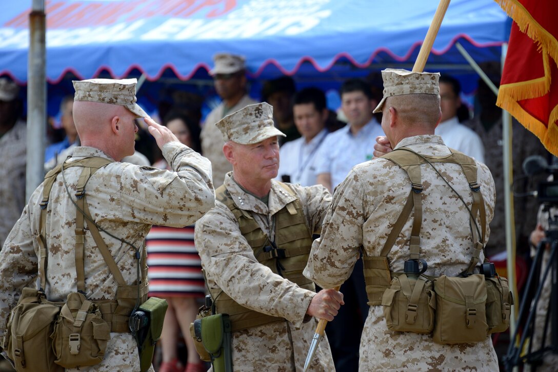 Lt. Gen. Kenneth J. Glueck Jr., center, passes the III Marine Expeditionary Force organizational colors to Lt. Gen. John E. Wissler July 19 at the Camp Foster parade deck during a change of command ceremony. “This tour has been the fastest two and a half years of my life but without a doubt the absolute most rewarding time in my career,” he said. “There is nothing better than being forward-stationed, forward-deployed, at the tip of the spear, a premier force in readiness; and having to actually show it and demonstrate it on a daily basis … that is truly rewarding,” said Glueck during his farewell address. (U.S. Marine Corps photo by Cpl. Mark W. Stroud/Released)