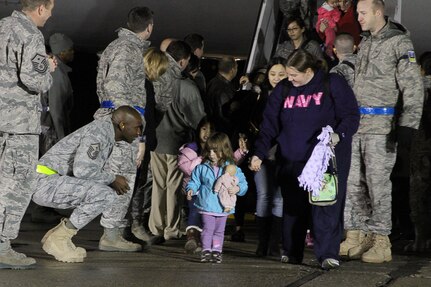 Master Sgt. Cory Gatewood, left, welcomes a Navy family to Travis Air Force Base after a flight from Japan. Volunteers from Naval Air Stations Lemoore and Fallon assisted Travis Air Force Base personnel with the arrival of military families voluntarily evacuating Japan. 