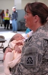 Lt. Col. Carrie Acree, Emergency Preparedness Liaison Officer, holds five-week old Adrian Morant while his mother gets situated at the Denver International Airport aerial port of debarkation March 24. More than 140 military dependents from Japan flew into DIA as part of Operation Pacific Passage, a voluntary departure operation that began after the earthquake and tsunami that struck Japan March 11. 