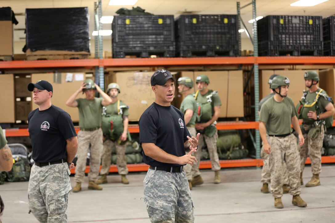 Jump Master Instructor Sgt. 1st Class Walter Veazey (right) instructs Marines with 2nd Marine Logistics Group and other units going through a jump master course aboard Camp Lejeune, N.C., July 19, 2013. The Marines in the course formed a circle where they could inspect one another’s equipment and learn what to look for during missions.  (U.S. Marine Corps photo by Lance Cpl. Shawn Valosin)