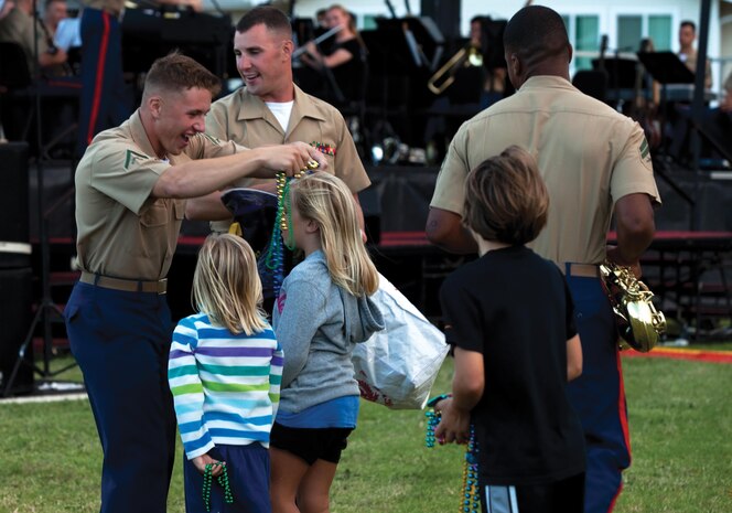 Lance Cpl. Bryan Sitka, trumpet player, U.S. Marine Corps Forces, Pacific Band, gives beads to the children at the Summer Concert Series at Mololani Park, July 12, 2013. (U.S. Marine Corps photo by Lance Cpl. Janelle Y. Chapman)