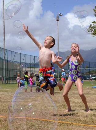 Henry Frazier, 4 (left) and his sister Madison, 11, attempt to catch bubbles during the Summer Splashdown at Riseley Field, July 13, 2013. Marine Corps Base Hawaii families engaged in numerous water activities at the event. (U.S. Marine Corps photo by Kristen Wong)
