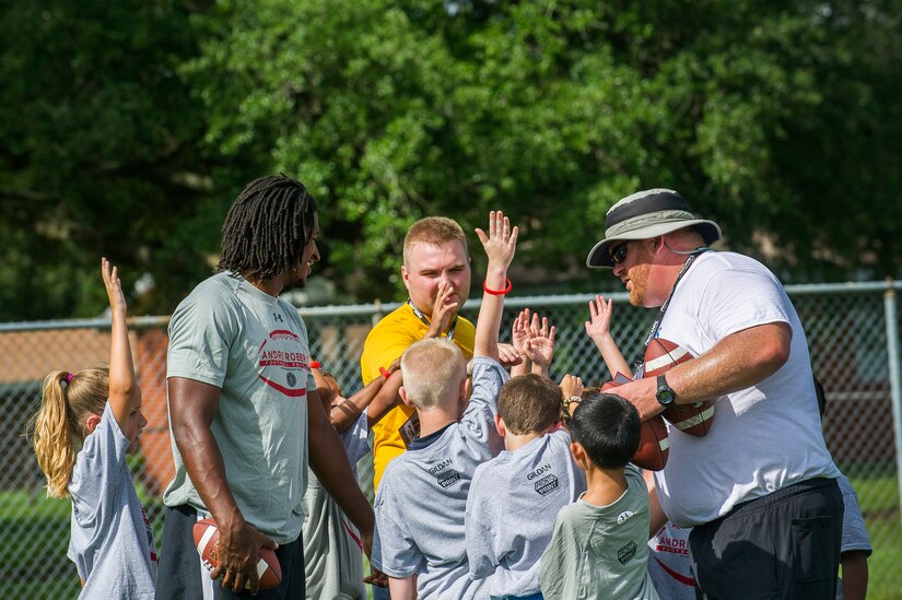 Andre Roberts, Arizona Cardinals wide receiver, comes in for a huddle with a training group of children during the Andre Roberts Pro Camp, July 15, 2013, at Joint Base Charleston - Weapons Station, S.C. More than 100 base children attended the Andre Roberts Pro Camp on July 15-16. The camp was paid for by Roberts, enabling the children to attend for free. (U.S. Air Force photo/ Senior Airman George Goslin)
