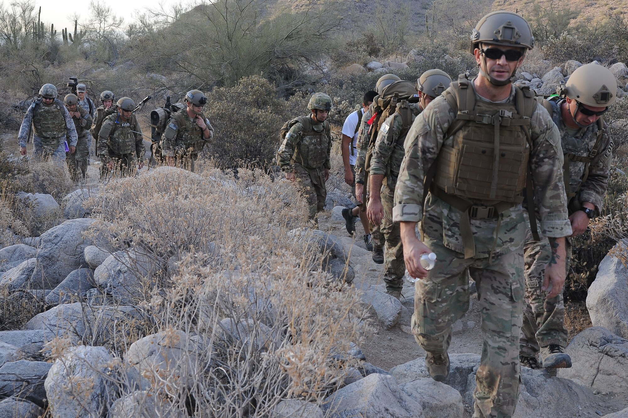 Explosive Ordnance Disposal members from the 56th Civil Engineer Squadron hike through rocky landscape July 3 with heavy gear in the hilly and steep terrain of White Tank Regional Park in Waddell. The off-base location provided an ideal training environment. (U.S. Air Force photo/Airman 1st Class James Hensley)
