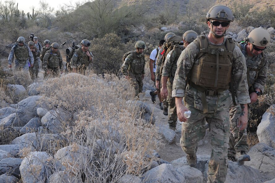 Explosive Ordnance Disposal members from the 56th Civil Engineer Squadron hike through rocky landscape July 3 with heavy gear in the hilly and steep terrain of White Tank Regional Park in Waddell. The off-base location provided an ideal training environment. (U.S. Air Force photo/Airman 1st Class James Hensley)