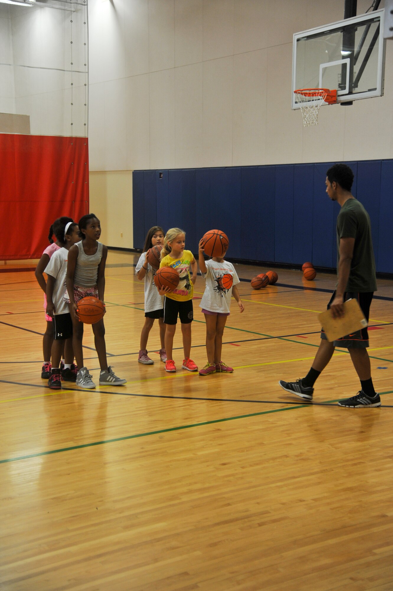 A group of the children at the youth center basketball summer camp work on shooting skills. The children were broken into two groups. The older children worked on advanced skills while the younger worked on dribbling, shooting and moving. (U.S. Air Force photo/Staff Sgt. C.J. Hatch)