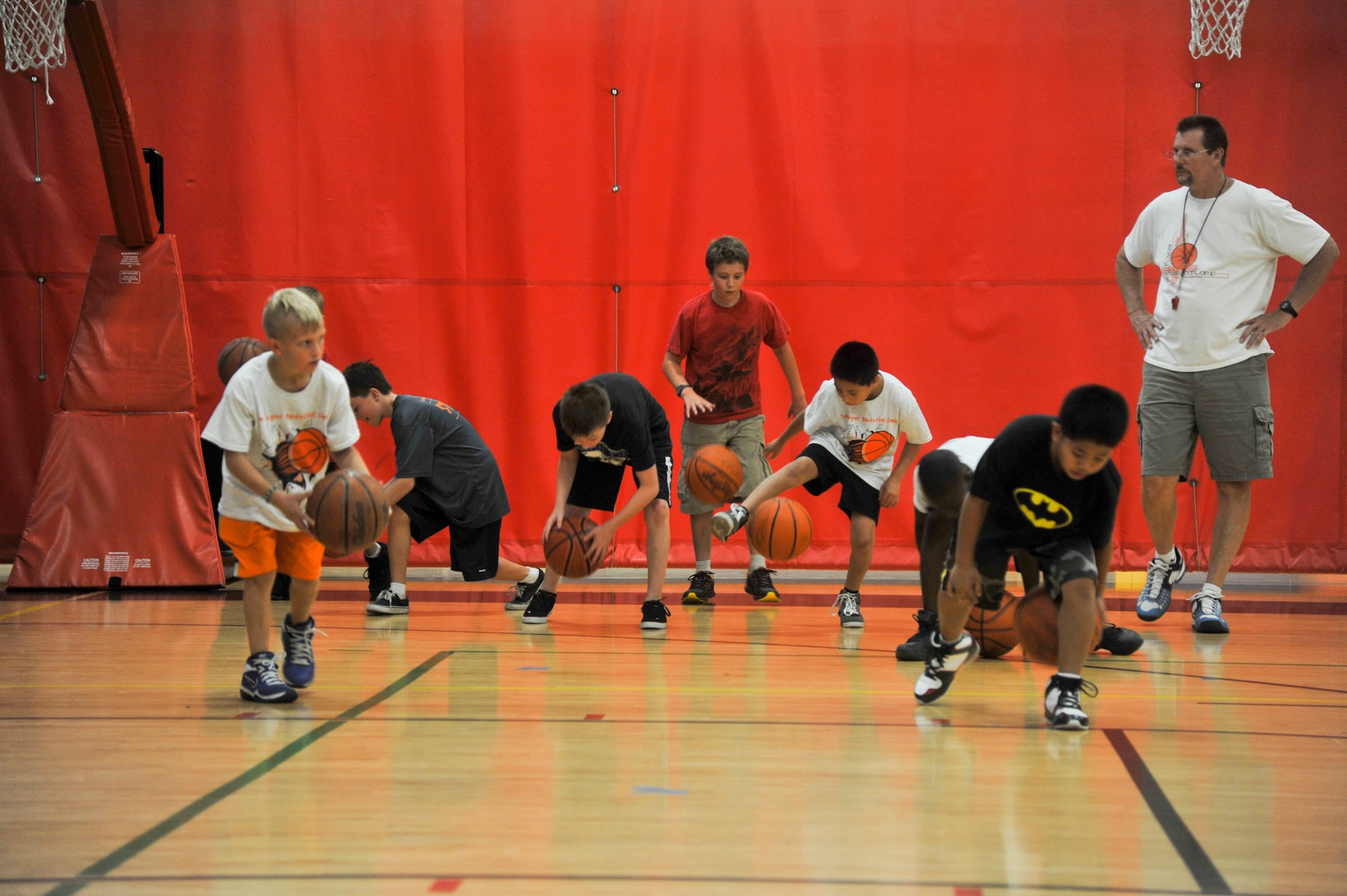 Tom Kuyper walks among the children participating in a basketball camp held July 8 through 12 at the Luke Air Force Base Youth Center. Kuyper helps the children with tips and pointers as they practice walking and dribbling between their legs. (U.S. Air Force photo/Staff Sgt. C.J. Hatch)