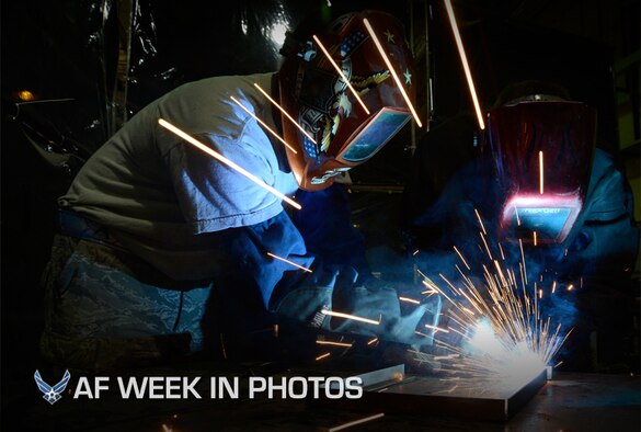 Senior Airman Kyle Zastrow performs an elbow weld while Senior Airman Isa Holland observes his work July 12, 2013, in Southwest Asia. Zastrow is using a metal inert gas welder and being trained on welding, which is not typical work for his career field. Holland is his trainer and will provide guidance on several aspects of his job during their deployment. Both are members of the combat metals shop, which uses two different career fields for a broader capability. Zastrow and Holland are deployed to the 386th Expeditionary Maintenance Squadron. (U.S. Air Force photo/Master Sgt. Christopher A. Campbell)