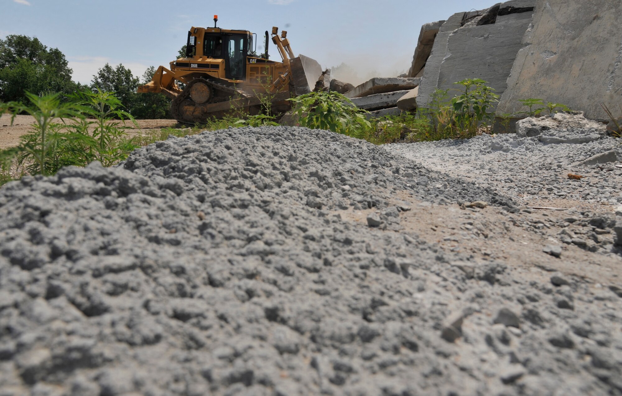 Airman 1st Class Brayden Lee, 509th Civil Engineer Squadron pavements and construction equipment journeyman, hauls crushed concrete using a front end loader at Whiteman Air Force Base, Mo., June 9, 2013. Front end loaders are used year round to repair damaged roads for Whiteman personnel to commute to and from their workplace. (U.S. Air Force photo by Airman 1st Class Keenan Berry/Released)