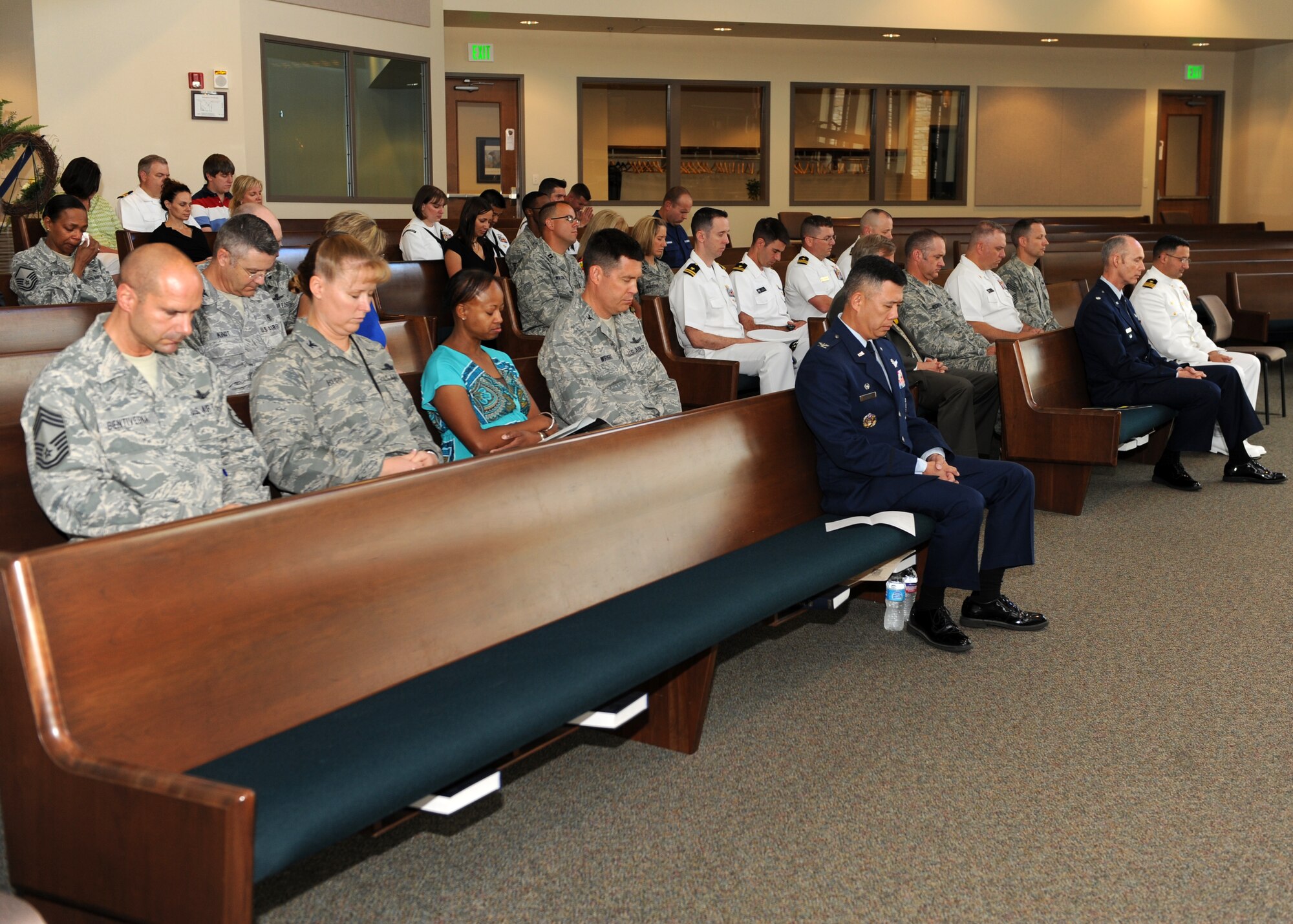Col. Dan Wright, 460th Space Wing commander; Col. Robert Uemura, 460th Mission Support Group commander; Col. DeAnna Burt, 460th Operations Group commander; Chief Master Sgt. John Bentivegna, 460th OG chief enlisted manager, bow their heads during prayer July 19, 2013, at Buckley Air Force Base, Colo. A 7/20 Service of Remembrance was held at the Buckley Chapel to honor Staff Sgt. Jesse Childress and Petty Officer 3rd Class John Larimer who were killed in the Aurora theater shooting July 20, 2012.    
