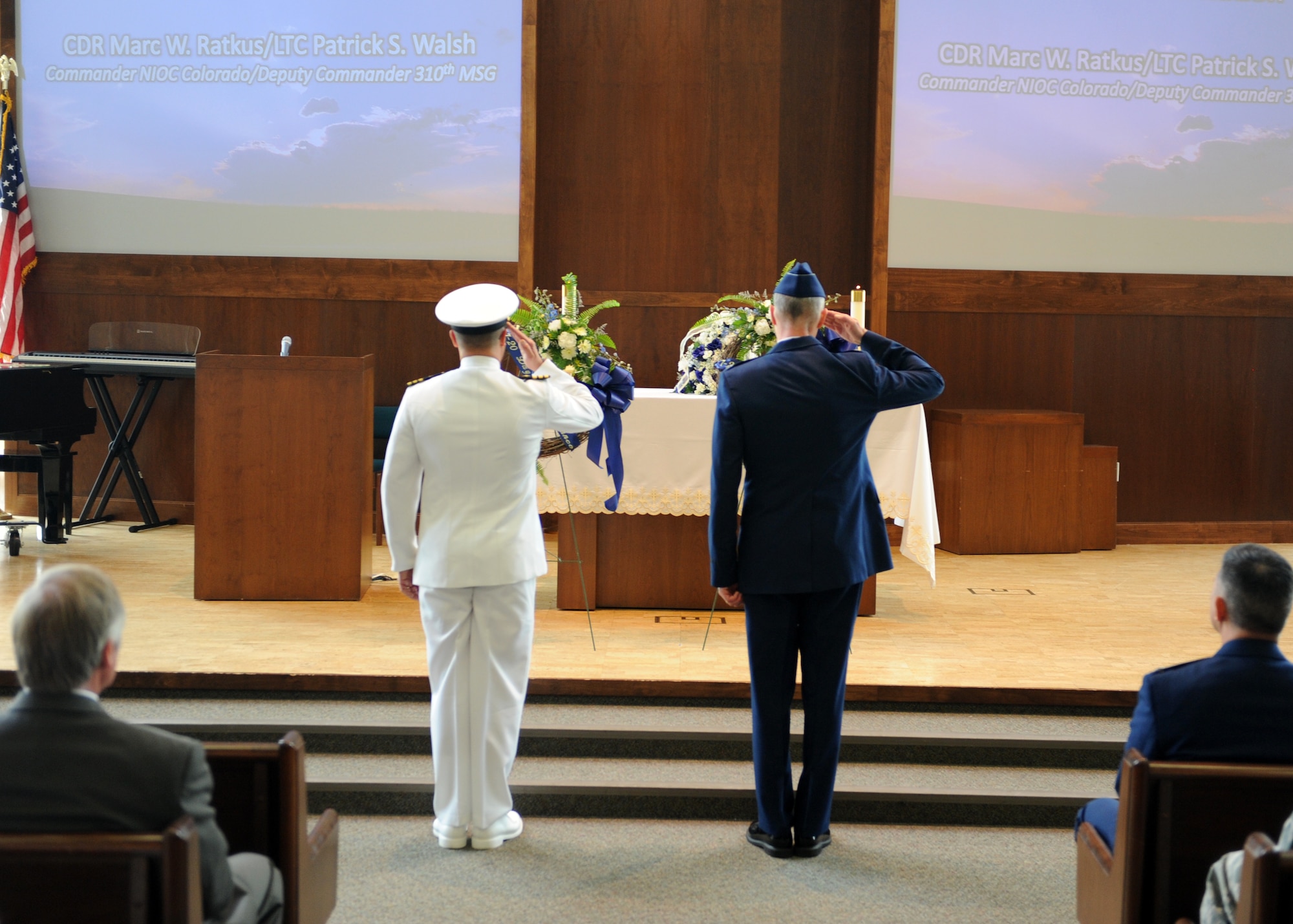 Cmdr. Marc Ratkus, Naval Intelligence Operations Center deputy commander, and Lt. Col. Patrick Walsh, 310th Mission Support Group commander, salute remembrance wreaths July 19, 2013, at Buckley Air Force Base, Colo. A 7/20 Service of Remembrance was held at the Buckley Chapel to honor Staff Sgt. Jesse Childress and Petty Officer 3rd Class John Larimer who were killed in the Aurora theater shooting July 20, 2012. (U.S. Air Force photo by Senior Airman Marcy Glass)