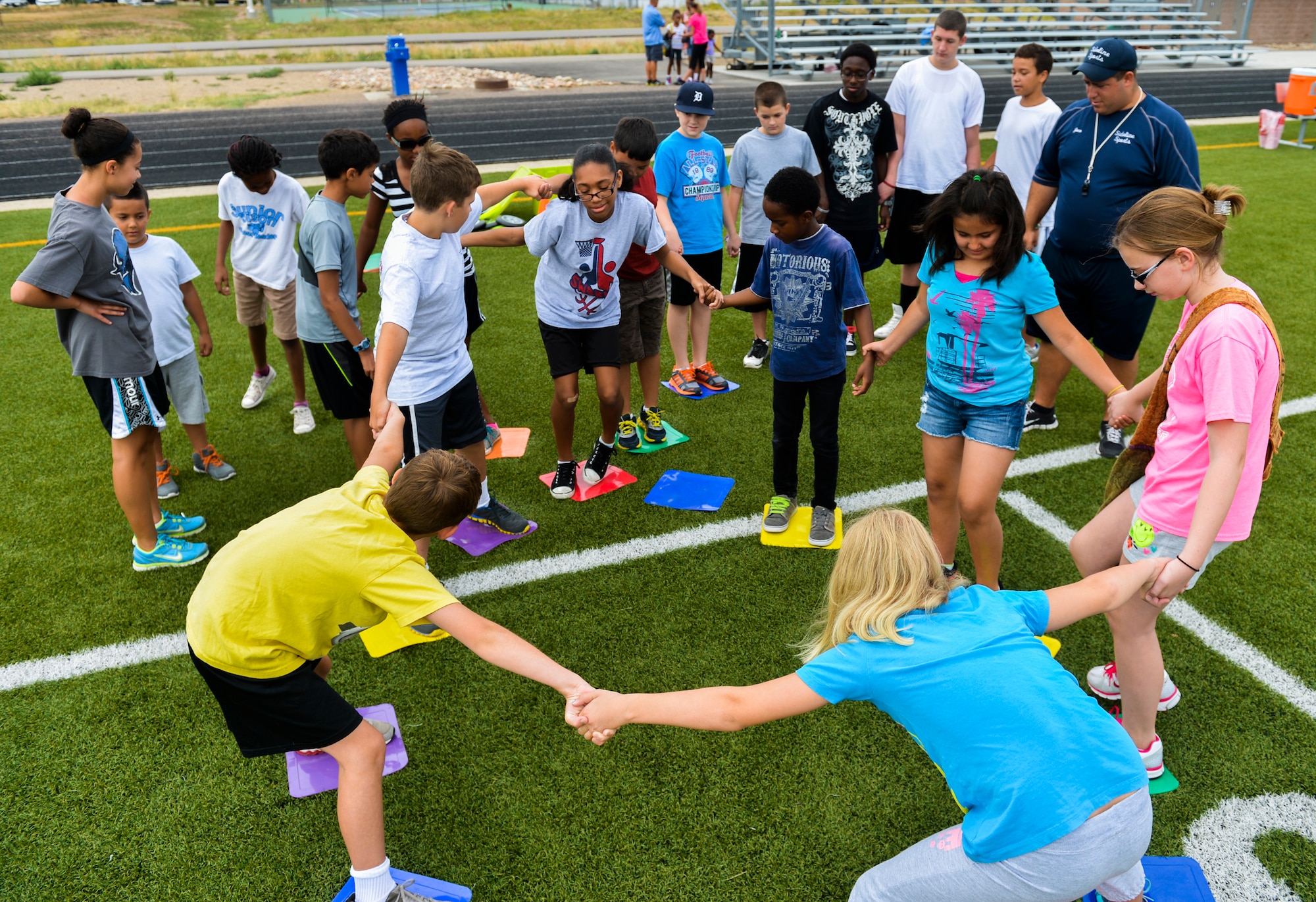 Youths participate in the magic bases team exercise during the Sidelines Sports Camp July 15, 2013, on Buckley Air Force Base, Colo. The exercise was used to teach youth communication, teamwork and listening skills they would need to complete tough tasks ahead of them throughout the weeklong camp. (U.S. Air Force photo by Staff Sgt. Paul Labbe/Released)