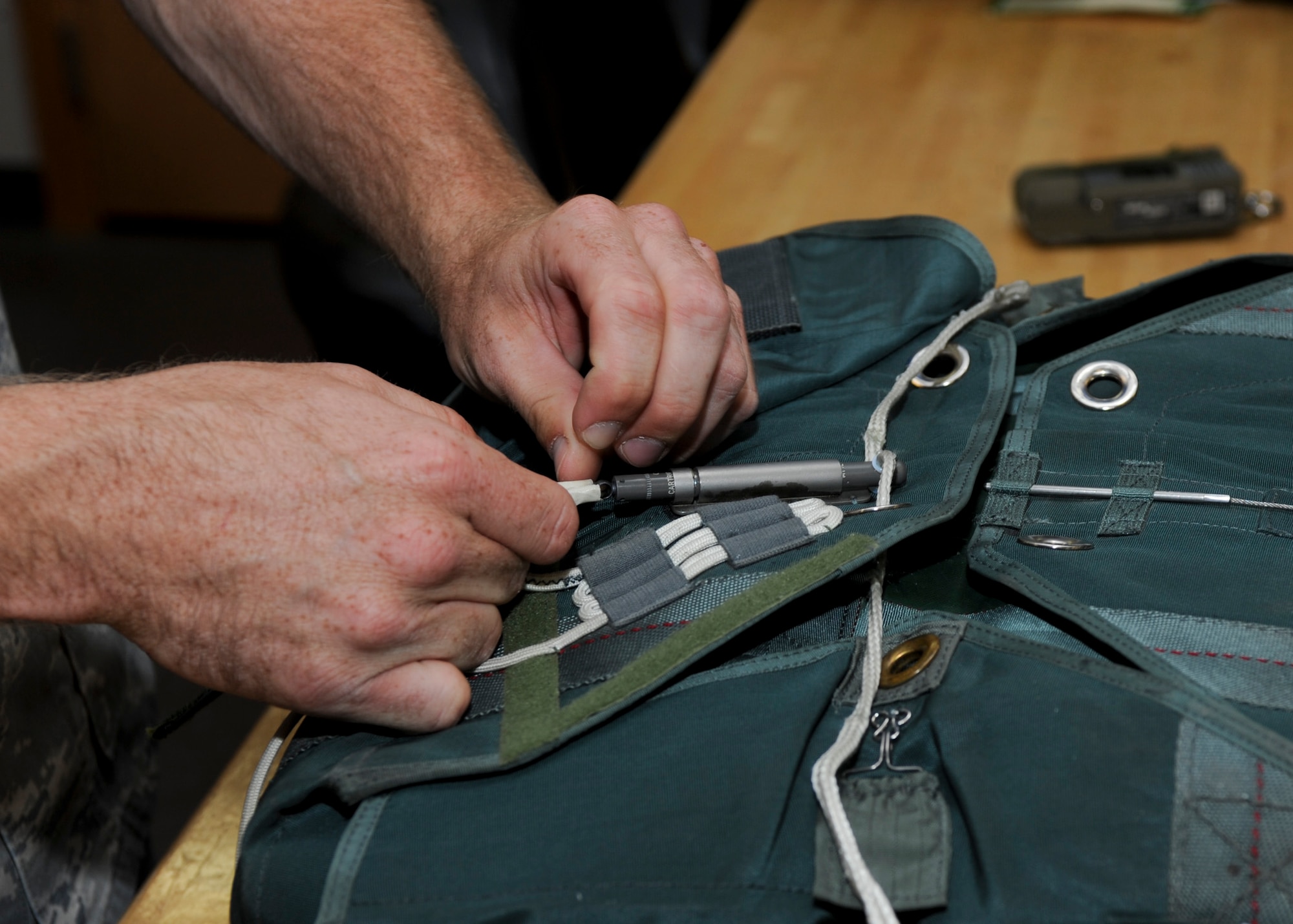 Staff Sgt. Jacob Wallenstein, 37th Bomb Squadron aircrew flight equipment technician and flightline supervisor, removes a cutter during an inspection of an Advanced Combat Ejection Systems kit at Ellsworth Air Force Base, S.D., July 16, 2013. The cutter is a small explosive device that will cut through the strings opening up the whole kit releasing survival equipment to include a floatation raft. (U.S. Air Force photo Airman 1st Class Anania Tekurio/Released)