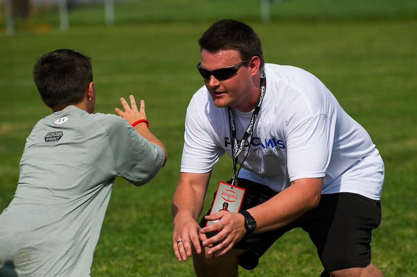 Jeff Cousins, West Ashley High School football coach, demonstrates how to block during the Andre Roberts Pro Camp, July 15, 2013, at Joint Base Charleston - Weapons Station, S.C. More than 100 base children attended the Andre Roberts Pro Camp on July 15-16. The camp was paid for by Roberts, enabling the children to attend for free. (U.S. Air Force photo/ Senior Airman George Goslin)