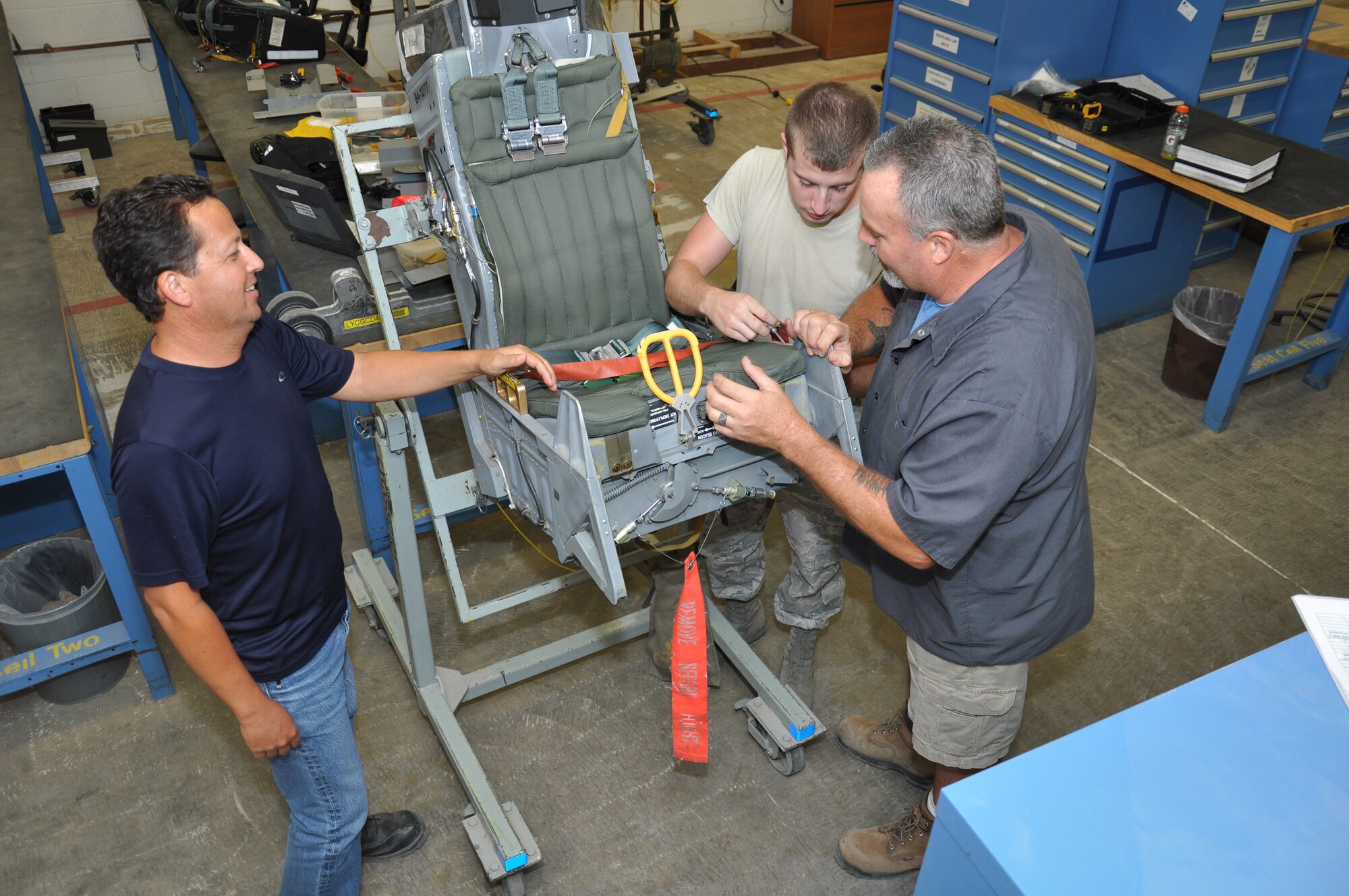 FROM LEFT: Luis Berrelez, Airman 1st Class Cameron Weston and Harry Webber, 56th Component Maintenance Squadron, examine the ACES II ejection seat July 9 at the 56th CMS egress section. Aircrew egress systems specialists maintain and repair items associated with aircraft escape and survival systems such as warning lights, emergency oxygen systems, canopies, lap belts and shoulder harnesses. (U.S. Air Force photo/Staff Sgt. Luther Mitchell Jr.)