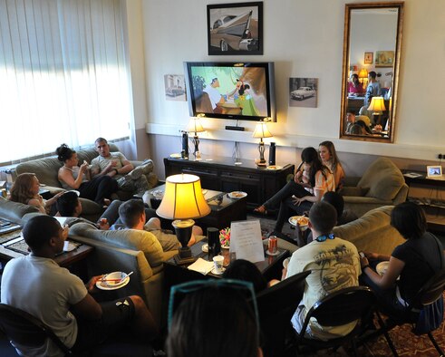 Airmen watch a movie and enjoy a home-cooked meal in the living room of Club 7. Club 7 is the place to go to build a healthy community amongst single Airmen living in the dorms. (U.S. Air Force photo/Airman Dymekre Allen)